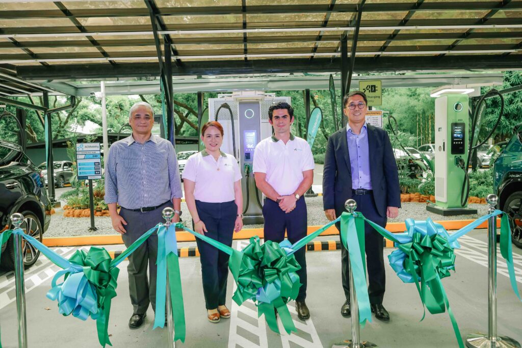 Four executives from ACMobility and partner organizations pose in front of a ribbon-cutting setup at the launch of the Philippines’ fastest EV chargers. Behind them are newly installed green fast-charging units under a covered EV charging bay, with signage indicating 240 kW and 480 kW capabilities. The atmosphere is professional and celebratory, marking a key milestone in sustainable urban mobility.