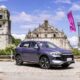 A BYD Sealion 5 DM-i in Deep Sea Blue is parked in front of the historic Paoay Church in Ilocos Norte, with pink flags waving in the background under a bright blue sky.