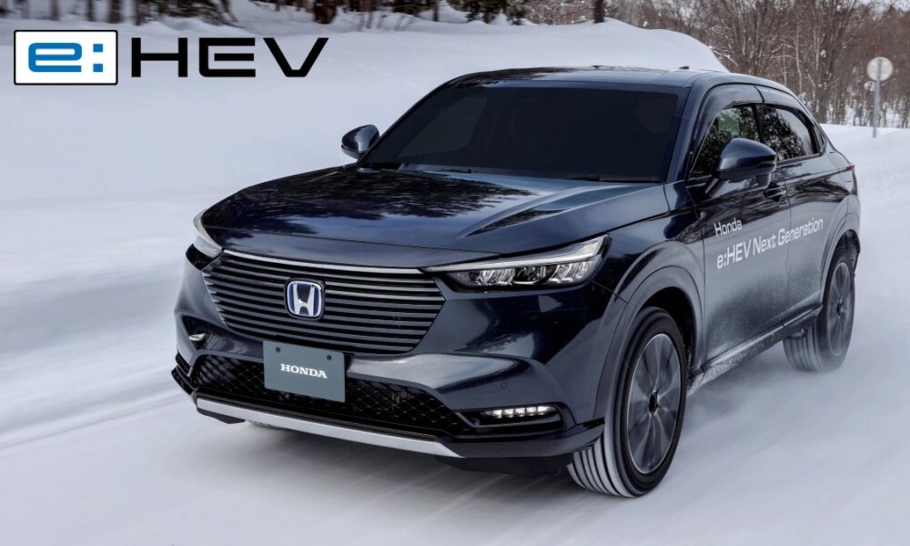 A sleek black Honda e:HEV Next Generation hybrid SUV driving confidently on a snowy road, showcasing its electric all-wheel drive capability. The vehicle kicks up snow as it maintains traction, with the e:HEV logo in the upper left corner of the image.