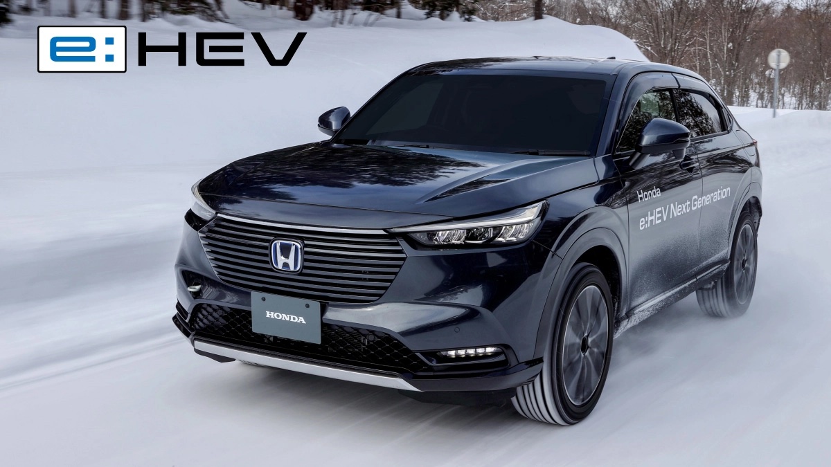 A sleek black Honda e:HEV Next Generation hybrid SUV driving confidently on a snowy road, showcasing its electric all-wheel drive capability. The vehicle kicks up snow as it maintains traction, with the e:HEV logo in the upper left corner of the image.