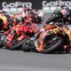MotoGP riders leaning into a high-speed corner during the Czech Sprint Race, led by KTM and Ducati bikes with multiple riders close behind.