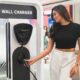 Woman smiling while holding the plug of a BYD electric vehicle wall charger at an indoor exhibit. Let me know if you need more images captioned or want to feature this on your site or socials!