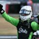 Nico Hulkenberg in green-and-black racing gear raises his fists in celebration after securing third place at the 2025 British Grand Prix.