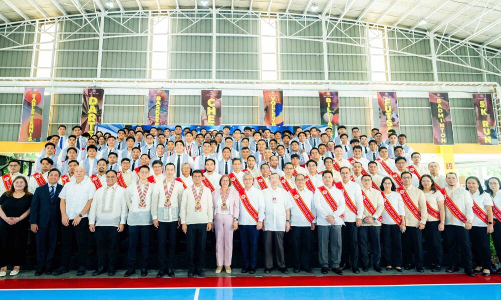 A large group photo of TMP Tech graduates and faculty members posing indoors during the 14th commencement ceremony, with graduates wearing sashes and formal attire.