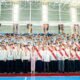 A large group photo of TMP Tech graduates and faculty members posing indoors during the 14th commencement ceremony, with graduates wearing sashes and formal attire.