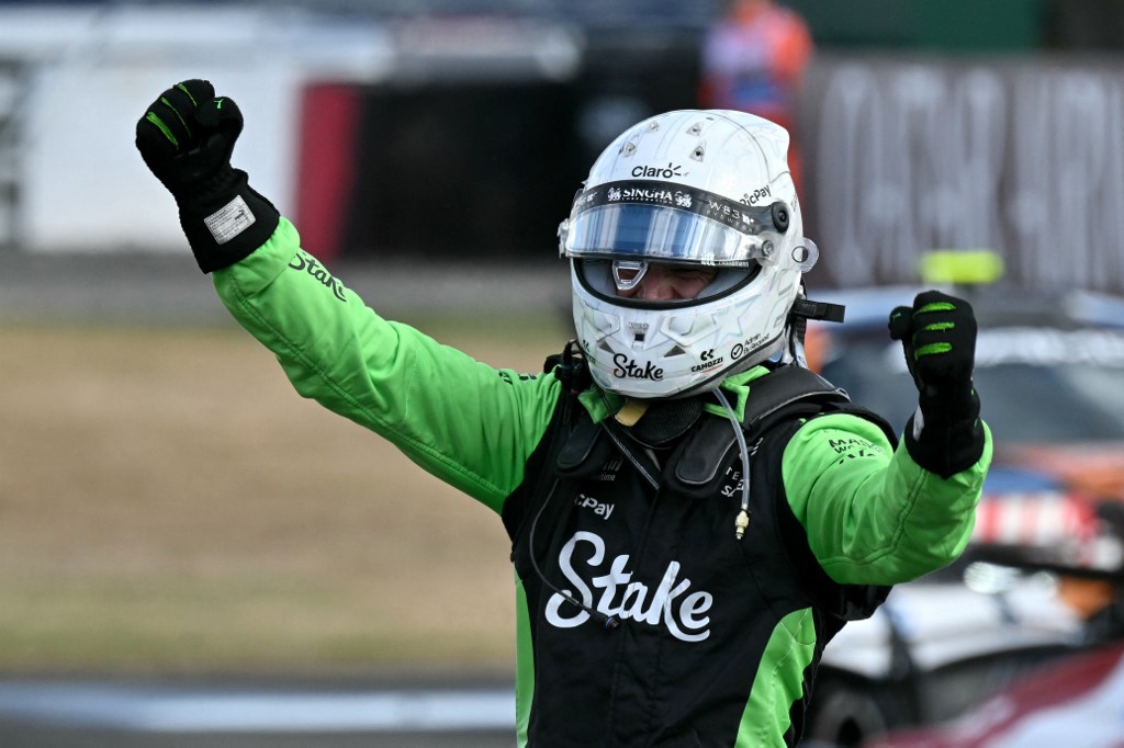 Nico Hulkenberg in green-and-black racing gear raises his fists in celebration after securing third place at the 2025 British Grand Prix.