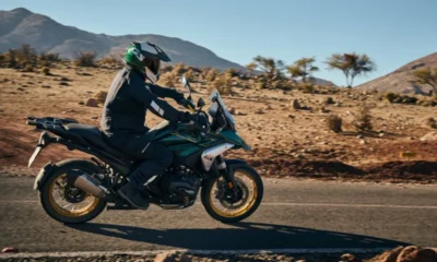 Rider on a BMW R 1300 GS Option 719 motorcycle traversing a desert road with mountainous terrain in the background.