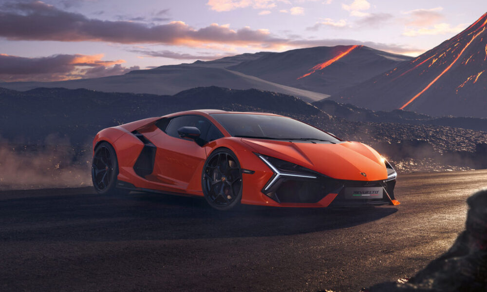 Bright orange Lamborghini Revuelto hybrid supercar parked on a rugged volcanic landscape at sunset, with glowing lava trails on mountains in the background.