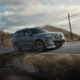 BMW X7 xDrive40d luxury SUV driving on a winding mountain road under a cloudy sky.