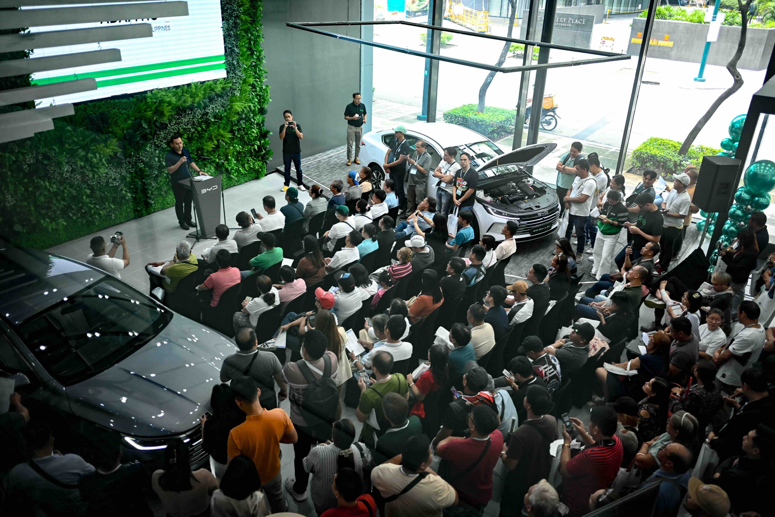 A crowd of GrabCar drivers attends a presentation during the BYD Grab Day Caravan at BYD Global City, with a BYD Seal 5 DM-i on display.