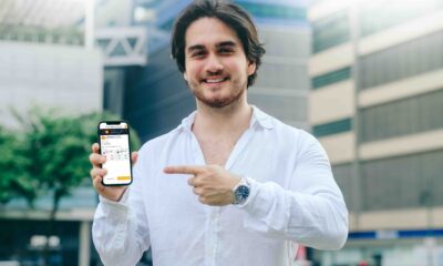 Man in white shirt smiles and points to a smartphone showing the Shell Recharge station on the Evro app.