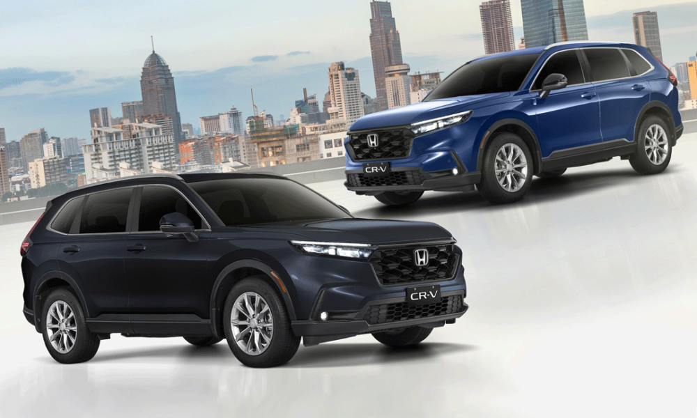 Two 2024 Honda CR-V VX Turbo CVT AWD units — one in Canyon River Blue Metallic and another in Meteoroid Gray Metallic — displayed with a modern city skyline in the background.