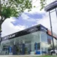 Exterior view of the newly opened Jetour Auto Santa Rosa dealership, featuring a sleek glass showroom, Jetour signage, and a tree-lined street under a partly cloudy sky.