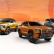 Lineup of Mitsubishi vehicles on display against an orange gradient backdrop featuring a Ferris wheel silhouette. Models shown include the Xpander, Xforce, Triton, Montero Sport, and L300.
