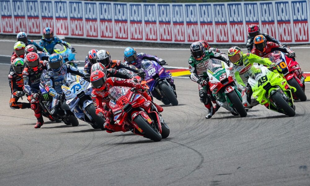 Marc Marquez leads the MotoGP pack into a turn at Sachsenring during the 2025 German Grand Prix, with riders closely trailing behind.