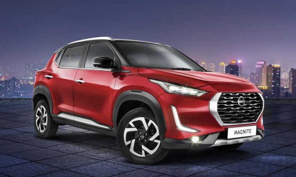 A red Nissan Magnite subcompact crossover parked on a tiled rooftop with a city skyline at night.