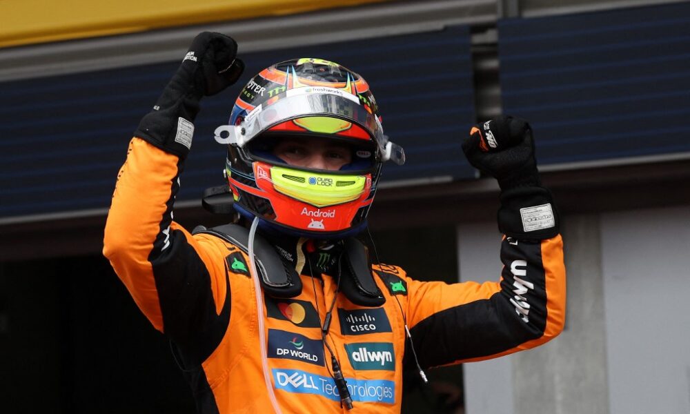 Oscar Piastri celebrates with raised fists while wearing his McLaren racing suit and helmet after winning the Belgian Grand Prix.