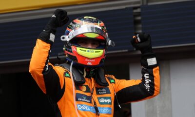 Oscar Piastri celebrates with raised fists while wearing his McLaren racing suit and helmet after winning the Belgian Grand Prix.