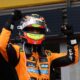 Oscar Piastri celebrates with raised fists while wearing his McLaren racing suit and helmet after winning the Belgian Grand Prix.