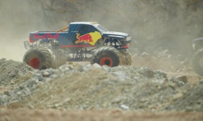 A Red Bull-branded mega truck kicks up dust as it roars through the rocky terrain of the Erzberg mine during an off-road race in Austria.