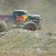 A Red Bull-branded mega truck kicks up dust as it roars through the rocky terrain of the Erzberg mine during an off-road race in Austria.