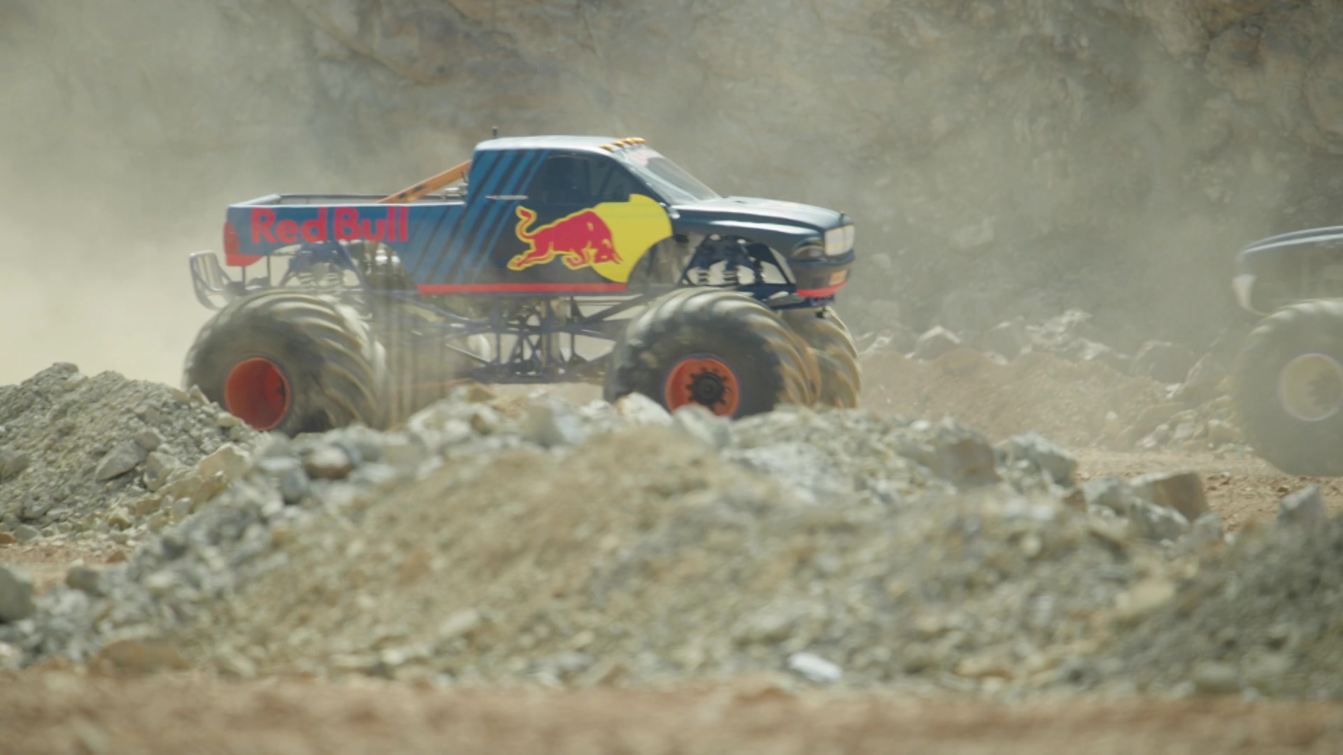 A Red Bull-branded mega truck kicks up dust as it roars through the rocky terrain of the Erzberg mine during an off-road race in Austria.