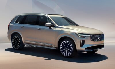 A beige Volvo XC90 T8 Ultra Plug-in Hybrid SUV parked on a minimalistic, desert-toned landscape with soft lighting and a pastel gradient sky. Text reads: “eXCeed standards. surpass aspirations.”