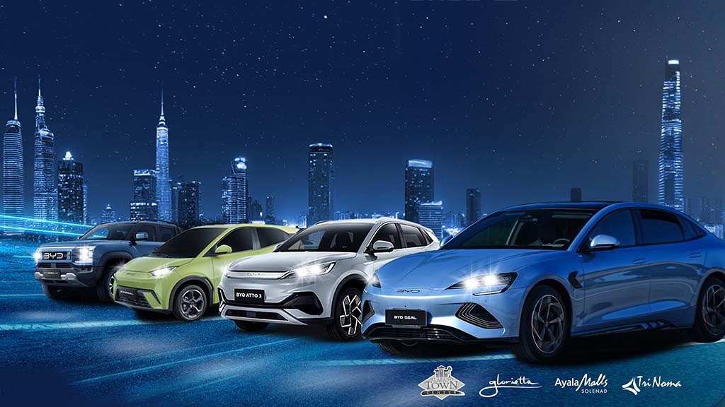Four BYD electric vehicles—the Shark 6, Seagull, Atto 3, and Seal 5—parked in front of a futuristic city skyline at night, with Ayala Malls logos beneath them.