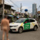 A Google Street View car drives through a typical Metro Manila neighborhood with overhead wires, aging apartment buildings, and a blurred naked figure in the foreground.