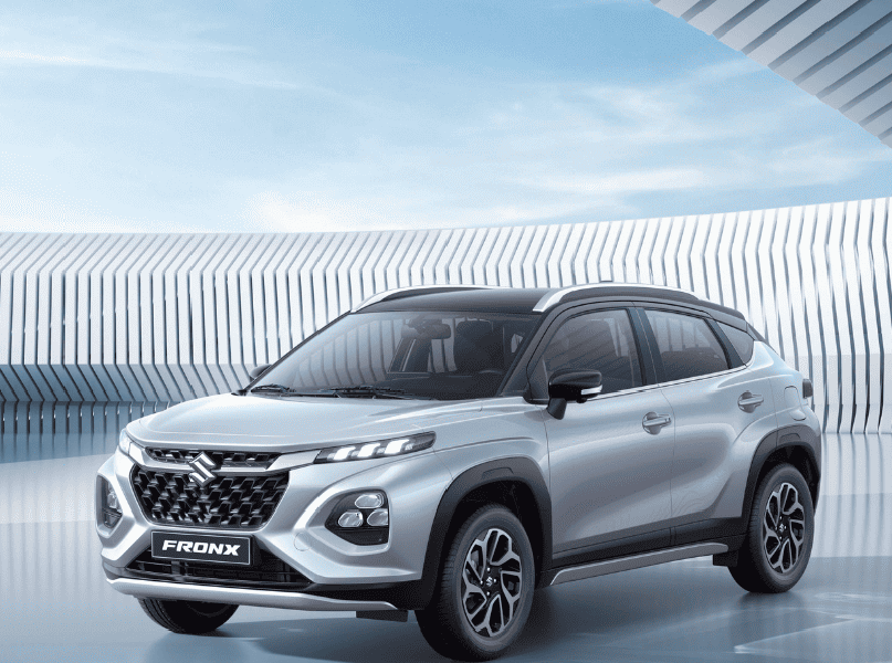 Silver Suzuki Fronx crossover parked in a modern architectural setting with geometric patterns in the background.