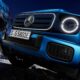 Close-up of the front grille and LED headlights of a blue Mercedes-Benz G 580 EQ, highlighting its modern electric design.