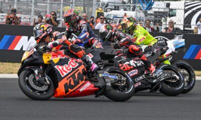 MotoGP riders tightly packed at the start of the Hungarian Sprint race, with KTM, Yamaha, and Aprilia bikes side by side in action.