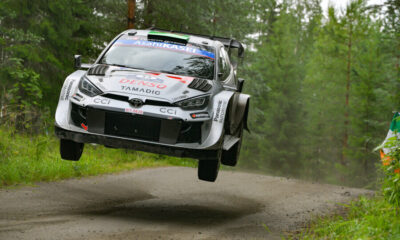 Toyota GR Yaris Rally1 airborne on a forest stage during Rally Finland, showcasing high-speed action and precision driving.