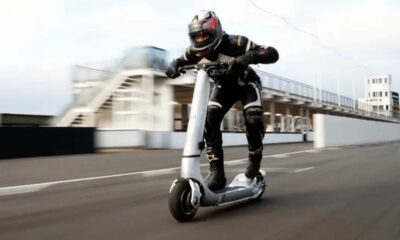 Rider in full racing gear riding a high-performance Bo Turbo electric scooter at high speed on a race track.