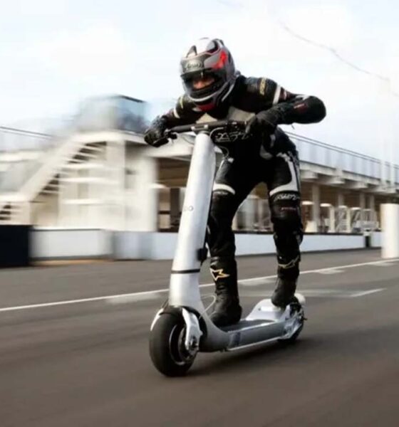 Rider in full racing gear riding a high-performance Bo Turbo electric scooter at high speed on a race track.