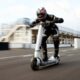 Rider in full racing gear riding a high-performance Bo Turbo electric scooter at high speed on a race track.