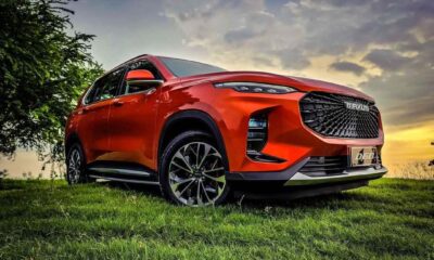 A striking red Maxus D60 SUV parked on a grassy field under a dramatic sunset sky.
