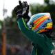 Fernando Alonso raises his hands in celebration while wearing his Aston Martin racing suit and helmet during the Hungarian Grand Prix weekend.