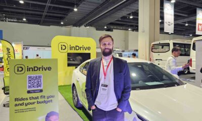 inDrive Regional Director Mark Tolley stands at the inDrive booth during the Philippine Commercial Vehicle Show 2025, with a white inDrive-branded car and promotional signage in the background.