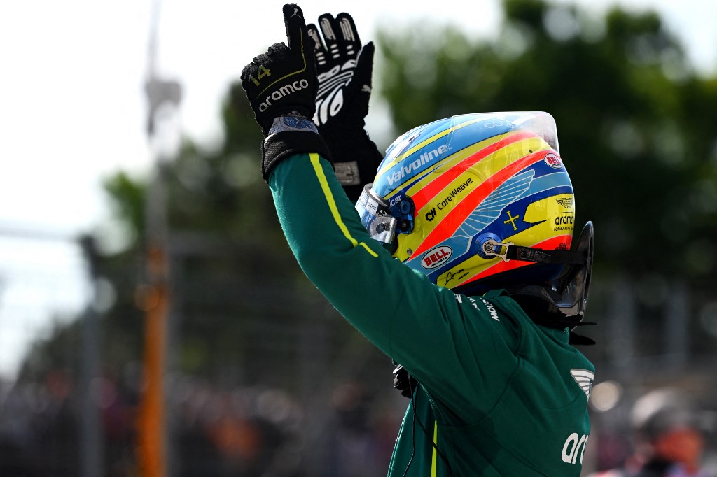 Fernando Alonso raises his hands in celebration while wearing his Aston Martin racing suit and helmet during the Hungarian Grand Prix weekend.