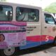 A white and pink Toyota Lite Ace community shuttle in Pasay City with a poster advertising “Libreng Sakay” (Free Ride) from Monday to Friday, 6 a.m. to 6 p.m., featuring Mayor Emi Calixto-Rubiano and the list of shuttle zones and stops.