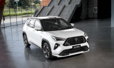 White Toyota Yaris Cross SE Hybrid Electric Vehicle displayed indoors with sporty black accents and alloy wheels.
