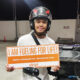 A smiling motorcycle rider wearing a helmet holds a sign that reads "I AM FUELING FOR LIFE!" at a Unioil station in Pasig.