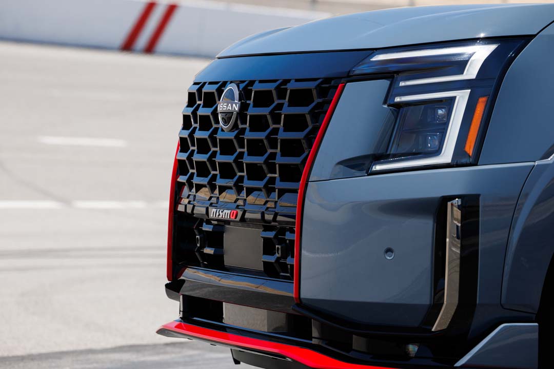 Close-up of the 2026 Nissan Armada NISMO front grille and headlight with red trim accents.