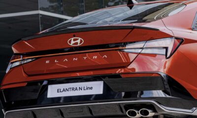 Rear view of the Hyundai Elantra N Line in red, showcasing its sporty bumper, dual exhausts, and bold taillight design.
