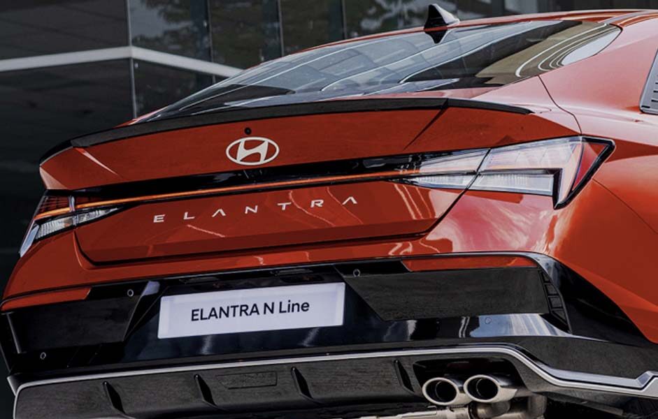 Rear view of the Hyundai Elantra N Line in red, showcasing its sporty bumper, dual exhausts, and bold taillight design.