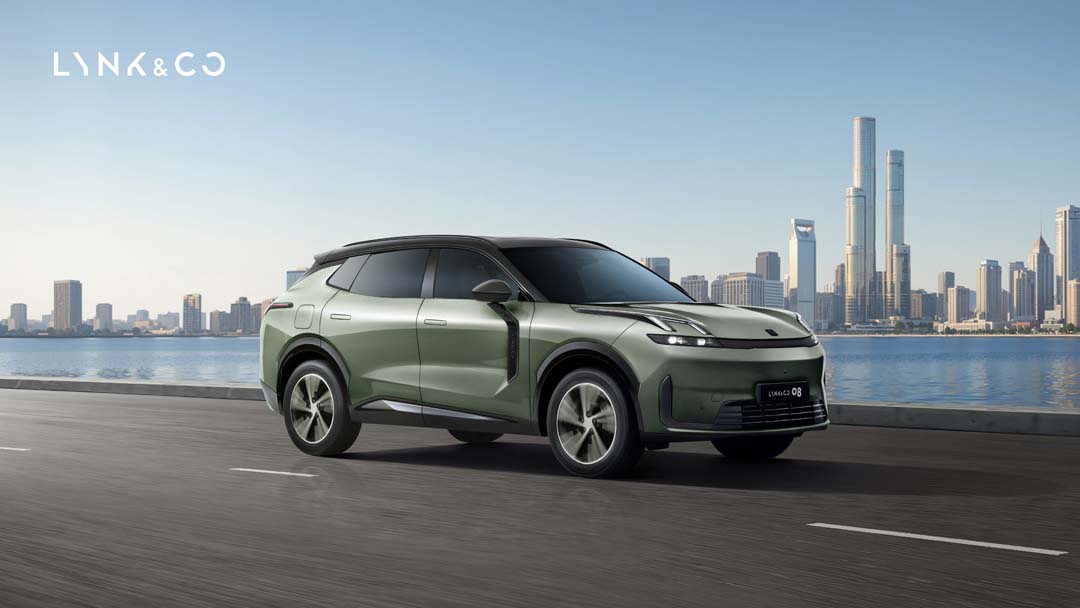 Lynk & Co 08 EM-P plug-in hybrid SUV in Mineral Green driving on a city road with skyline and waterfront in the background.