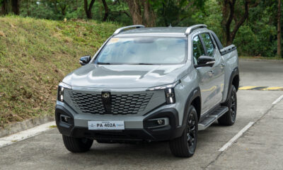 Front view of a gray Changan Nevo Hunter K50 range-extended electric pickup truck parked on a concrete road beside a grassy hillside.