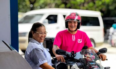 A smiling fuel station attendant assists a foodpanda rider on a motorcycle at a Caltex station.