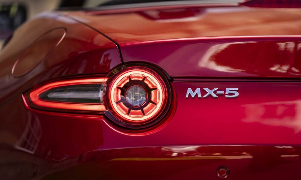 Close-up of the rear taillight and badge of a red Mazda MX-5 sports car.